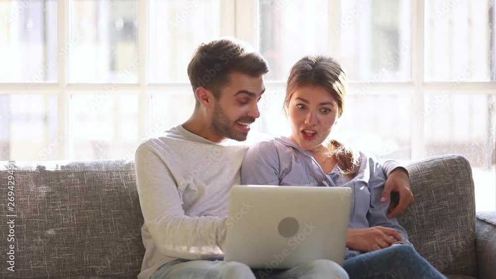 Excited young couple looking at laptop surprised by lottery win Excited young couple looking at laptop surprised by lottery win