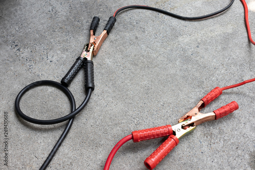 Jumper cables connect to another jumper cables for longer cables on cement ground.