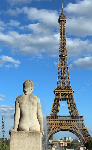 Statue of woman looks the big Eiffel Tower in Paris