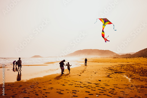 Silhouettes of people playing and flying a kite in sandy Golden Beach, Karpasia, Cyprus photo