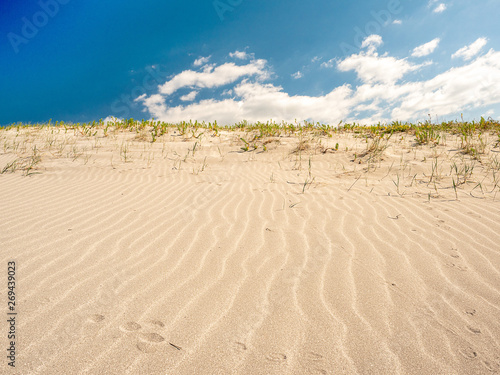 Sand pattern, blue cloudy sky. Warm summer day.