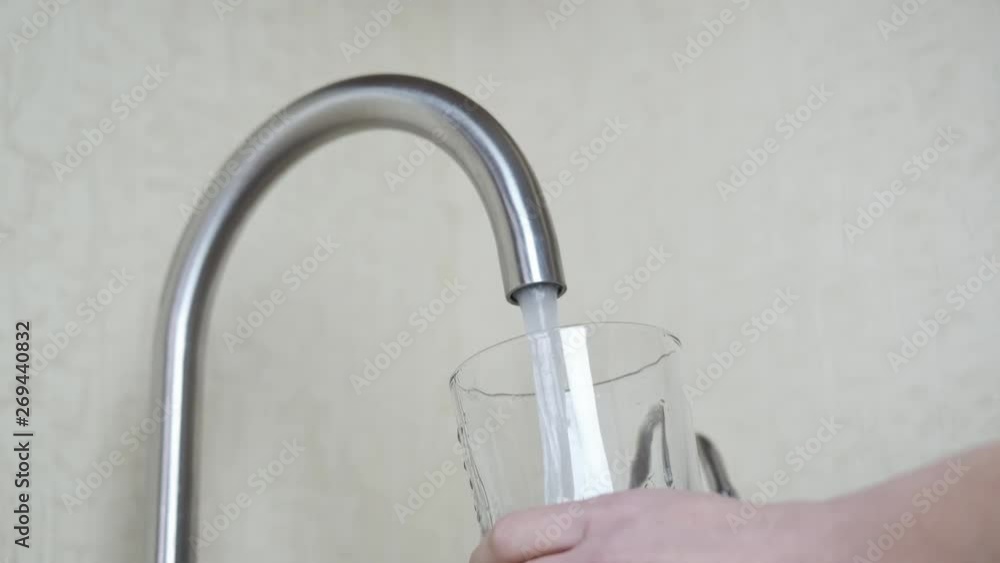 Pouring water into the glass from the tap. Pour running tap water into a glass beaker. Pouring water into the glass from the tap. Pour running tap water into a glass beaker.