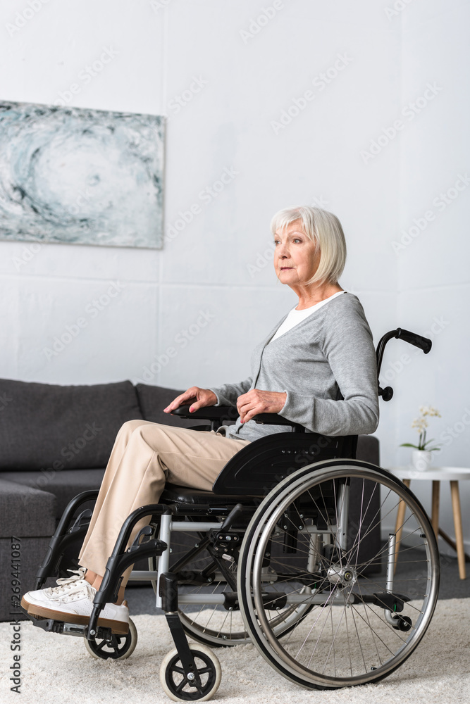 disabled senior woman sitting in wheelchair and looking away disabled senior woman sitting in wheelchair and looking away