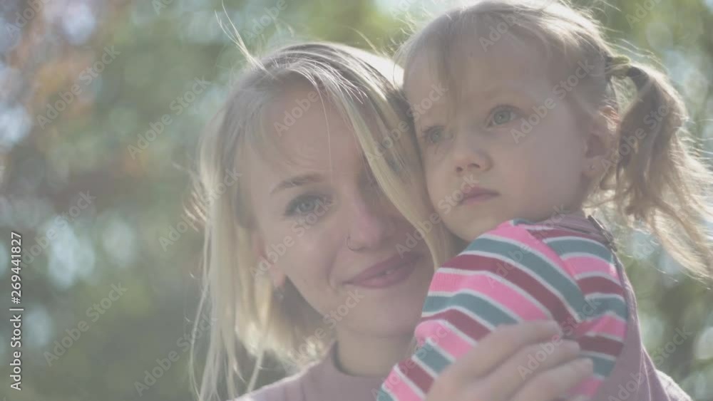 Portrait of young mother and amazing blond daughter at mothers hands Portrait of young mother and amazing blond daughter at mothers hands