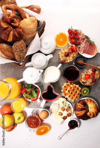 Huge healthy breakfast on table with coffee, orange juice, fruits, waffles and croissants. Good morning concept.