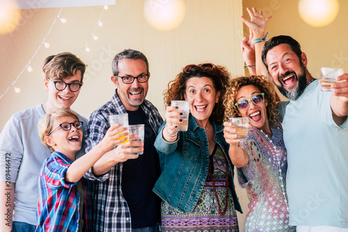 Group of people caucasian men and women different ages from children to teenager to adults enjoy and celenrate together toasting with glasses and having a lot of fun for friendship