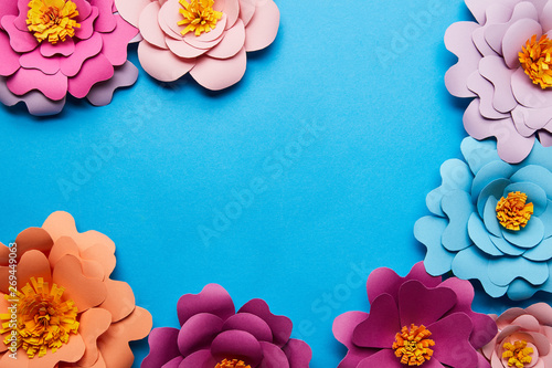 Fototapeta Naklejka Na Ścianę i Meble -  top view of multicolored paper cut flowers on blue background with copy space