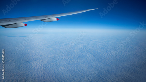 Close up of window with airplane wing. Beautiful cloudscape with clear blue sky.
