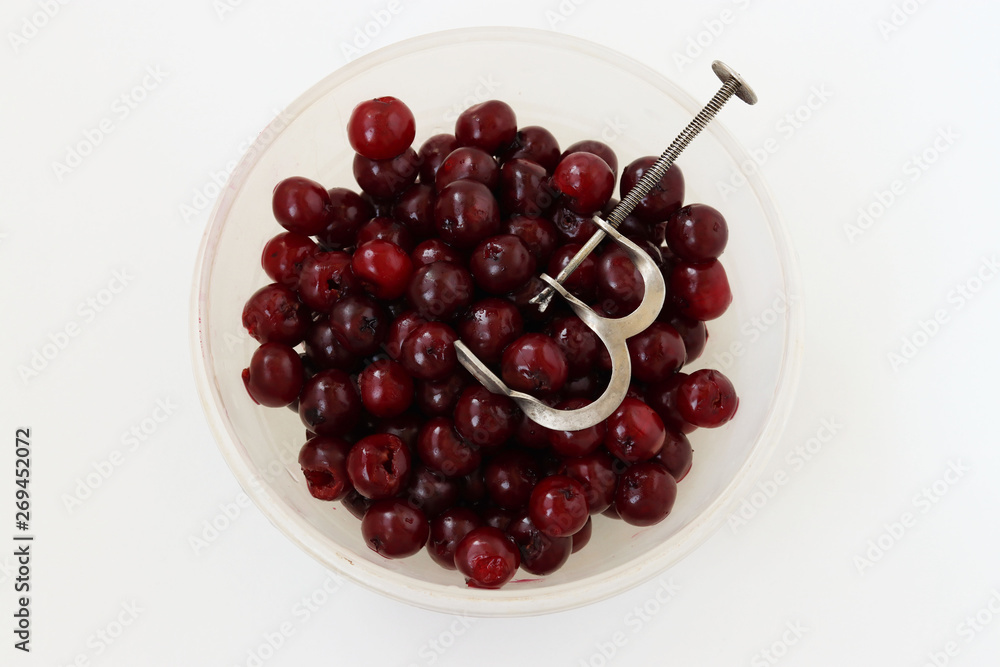 Fresh, seedless cherry is located in a bowl on a white background, Removal of bones from cherries by special adaptation Fresh, seedless cherry is located in a bowl on a white background, Removal of bones from cherries by special adaptation