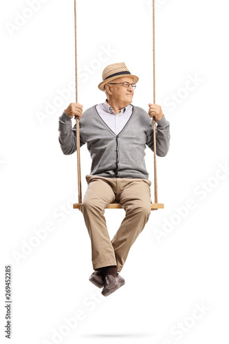 Senior man sitting on a swing and looking away