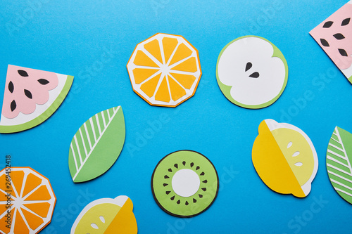top view of paper cut lemons, leaves, oranges, kiwi and watermelons on blue background