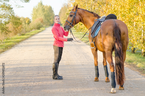 portrait of young woman and dressage horse in autumn landscape