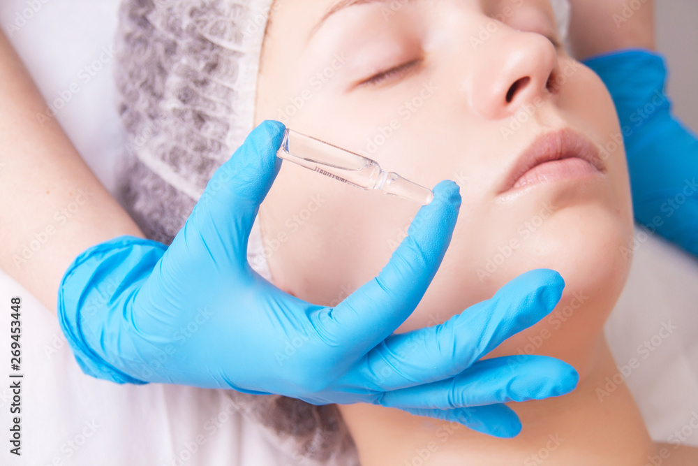 Cosmetic ampoule, a woman in the beauty salon. Vitamin in cosmetic ampoule. Cosmetic ampoule, a woman in the beauty salon. Vitamin in cosmetic ampoule.