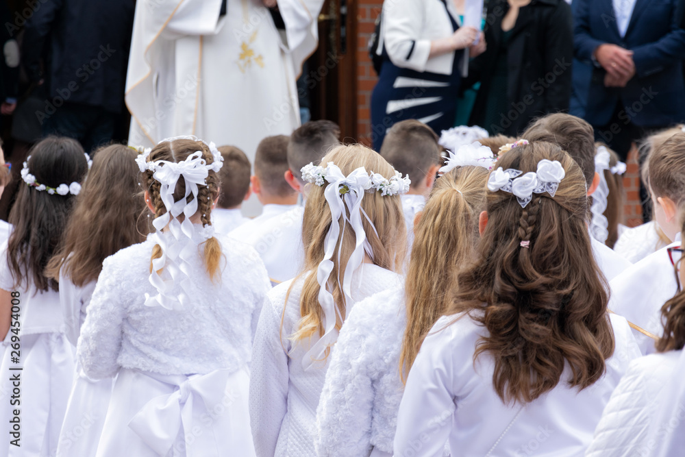 Children prepared for the first communion are waiting in front of the church.