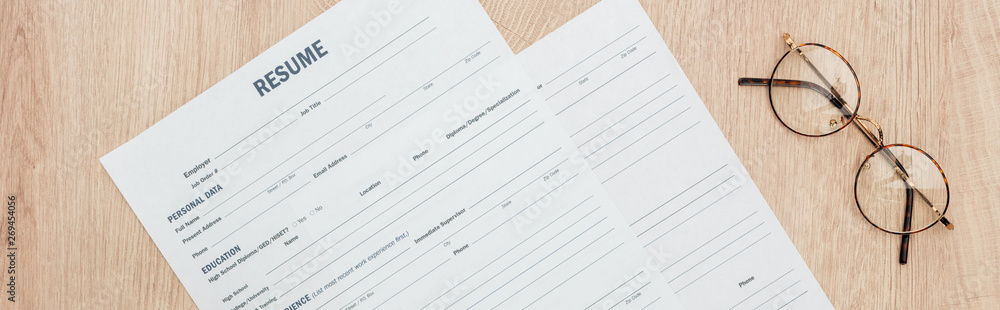 panoramic shot of resume templates and glasses on wooden surface panoramic shot of resume templates and glasses on wooden surface