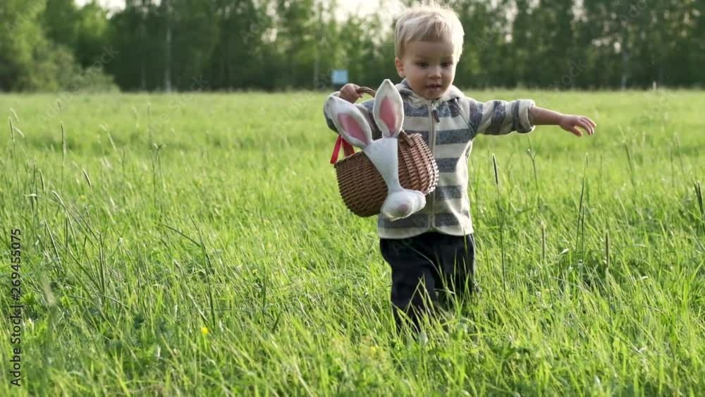 Adorable toddler kid with wicker basket an Easter egg hunt in green lawn or park. Easter celebration. Slow motion. Adorable toddler kid with wicker basket an Easter egg hunt in green lawn or park. Easter celebration. Slow motion.