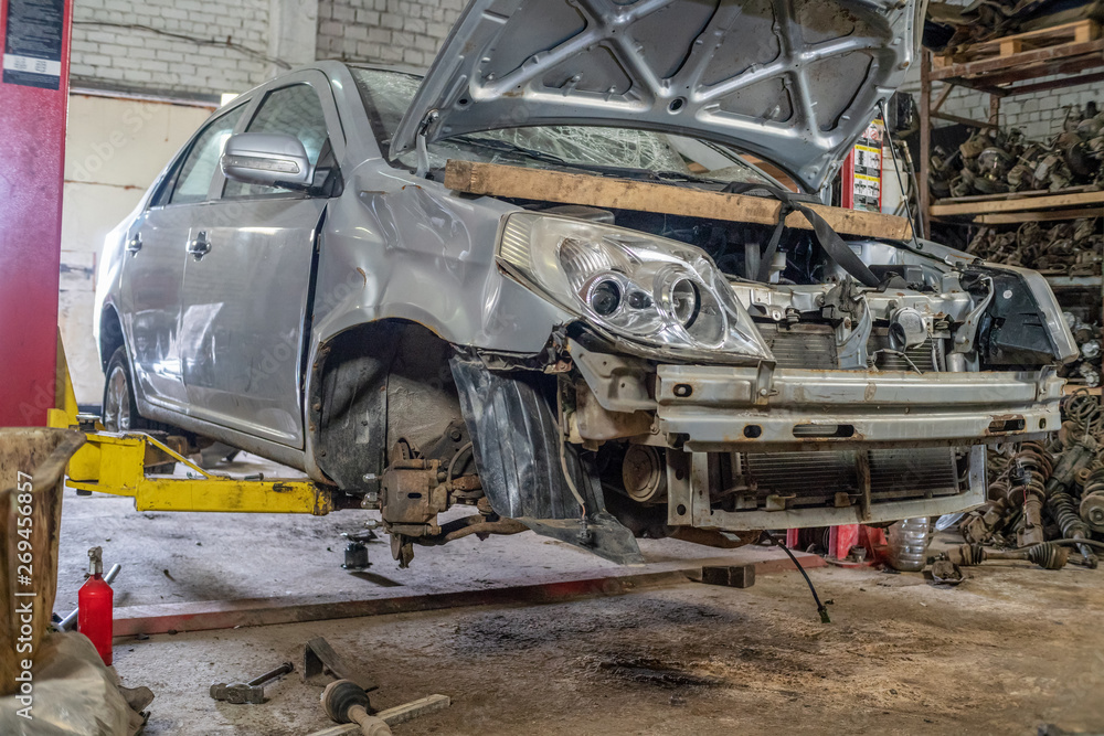 Close-up of a gray car with an open hood on a lift after an accident Close-up of a gray car with an open hood on a lift after an accident