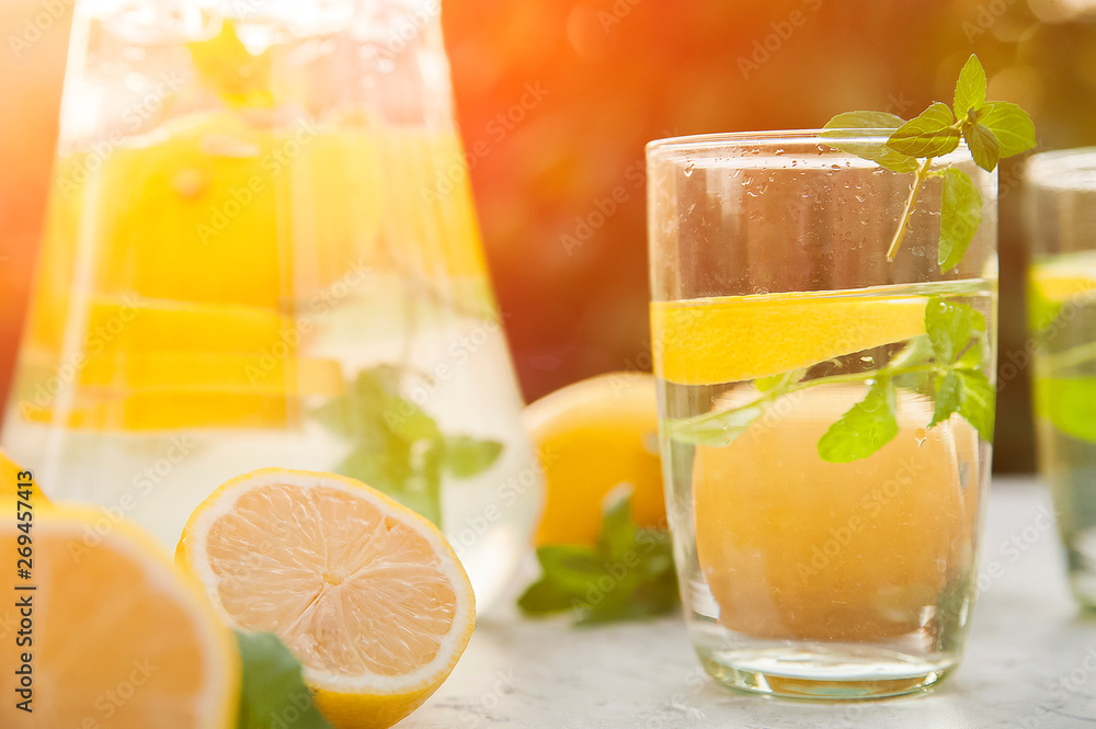 Fototapeta premium Homemade refreshing lemonade in decanter close-up and copy space. Lemonade from lemons, mint, ice.