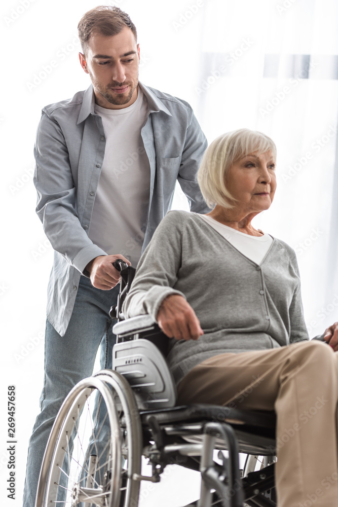 bearded man carrying disabled mother on wheelchair at home bearded man carrying disabled mother on wheelchair at home