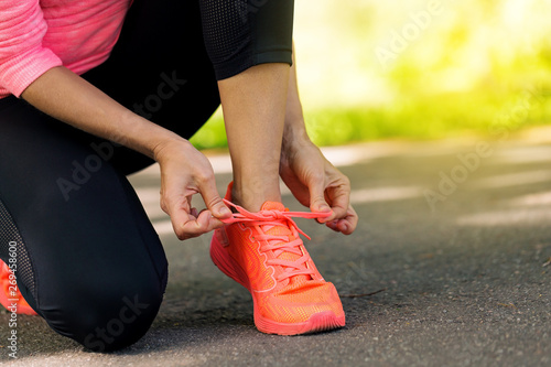 Runner woman tying up laces of shoes photo