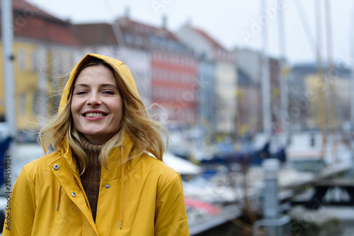 Denmark, Copenhagen, portrait of happy woman at city harbor in rainy weather