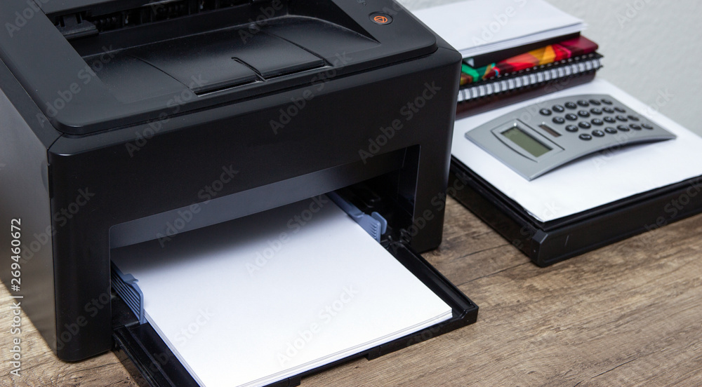 Laser printer and office supplies on the table. Laser printer and office supplies on the table.