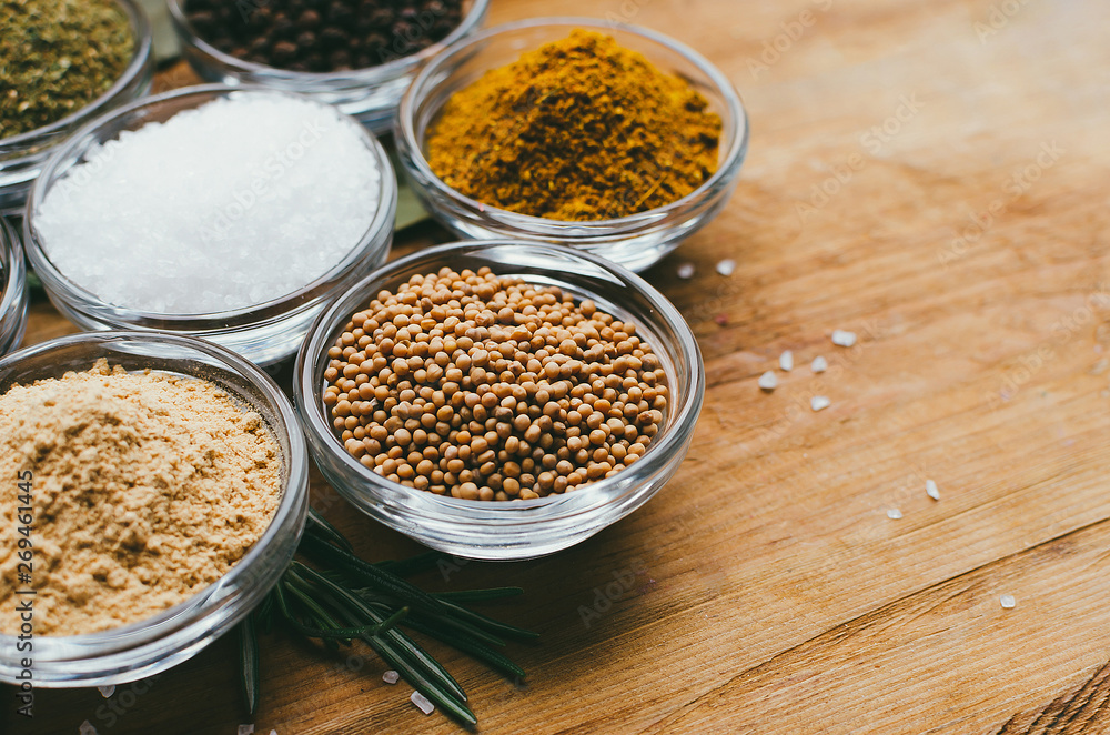 Variety of spices in round glass bowls - ground ginger, hops-suneli, kari, black pepper and mix Variety of spices in round glass bowls - ground ginger, hops-suneli, kari, black pepper and mix