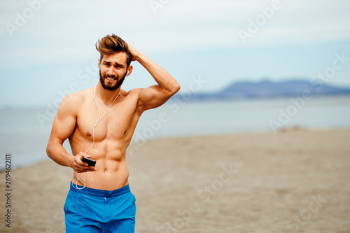 Handsome man on the beach listens to music over the earphones