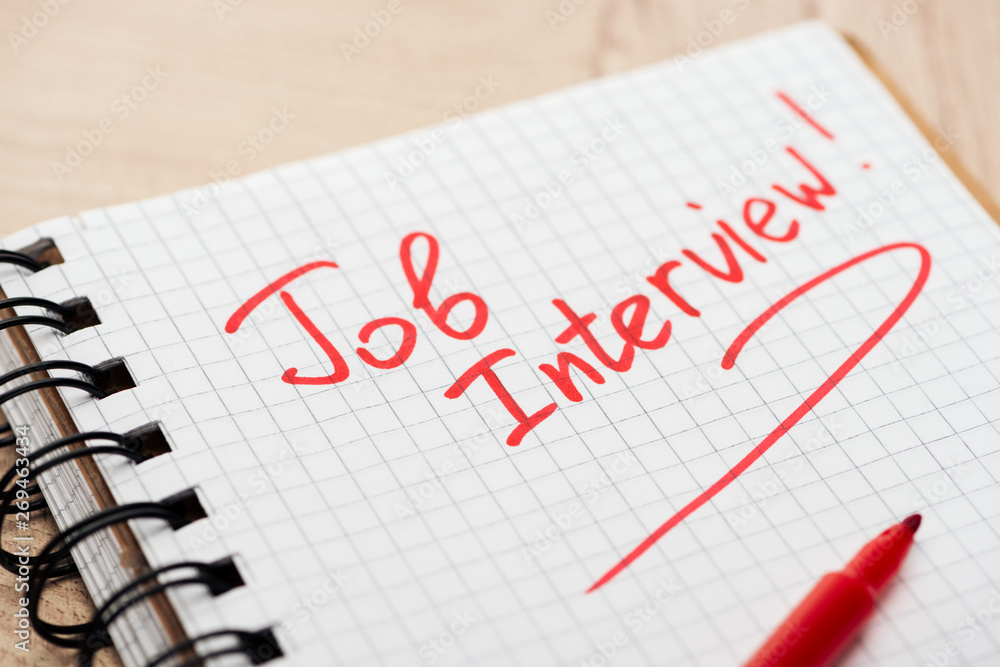 notebook with red job interview lettering and red marker on wooden table notebook with red job interview lettering and red marker on wooden table