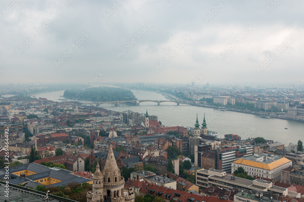 Fototapeta premium Budapest, Hungary. View of the city in cloudy weather from the tower of the Cathedral of St. Matthias. Danube River. Spring. Tourism and travel. Skyview. Top view.