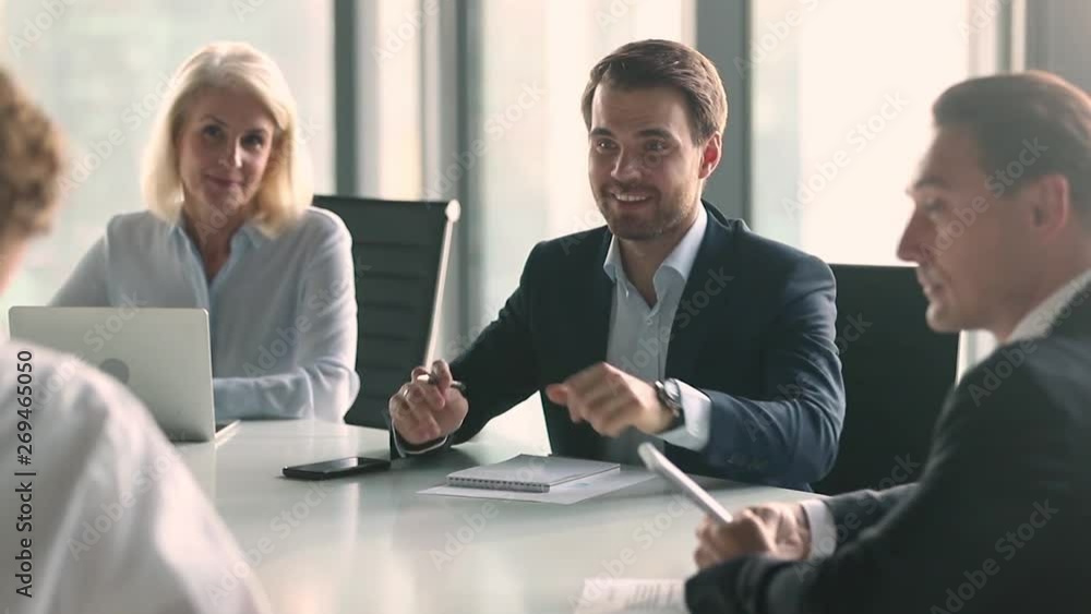 Businessman in suit talking to business people sitting at table Businessman in suit talking to business people sitting at table