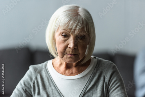 pensive senior woman with grey hair looking down