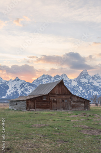 Infamous T.A. Moulton Barn during sunset in Mormon Row, Grand Teton National Park, Wyoming. Features backlit Teton peaks.