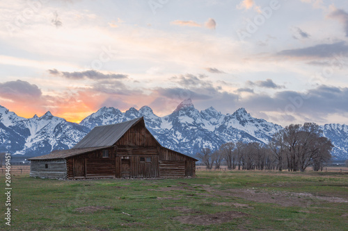 Infamous T.A. Moulton Barn during sunset in Mormon Row, Grand Teton National Park, Wyoming. Features backlit Teton peaks within the panorama.