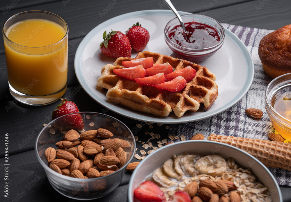 Breakfast. Oatmeal. Muesli. Snack. Sweet waffles. Morning fresh food. Berry, almond, jam, juice. Dessert on black table background. Top view Breakfast. Oatmeal. Muesli. Snack. Sweet waffles. Morning fresh food. Berry, almond, jam, juice. Dessert on black table background. Top view