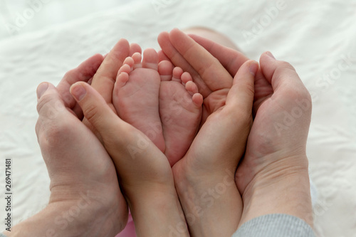 Closeup baby's feet in mother and father hands 