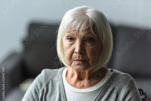 pensive senior woman with grey hair looking away