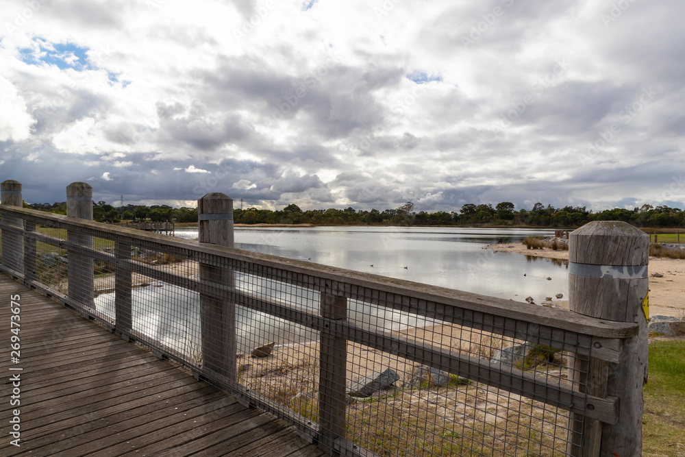 A walk bridge on a large fresh water lake in a community park.