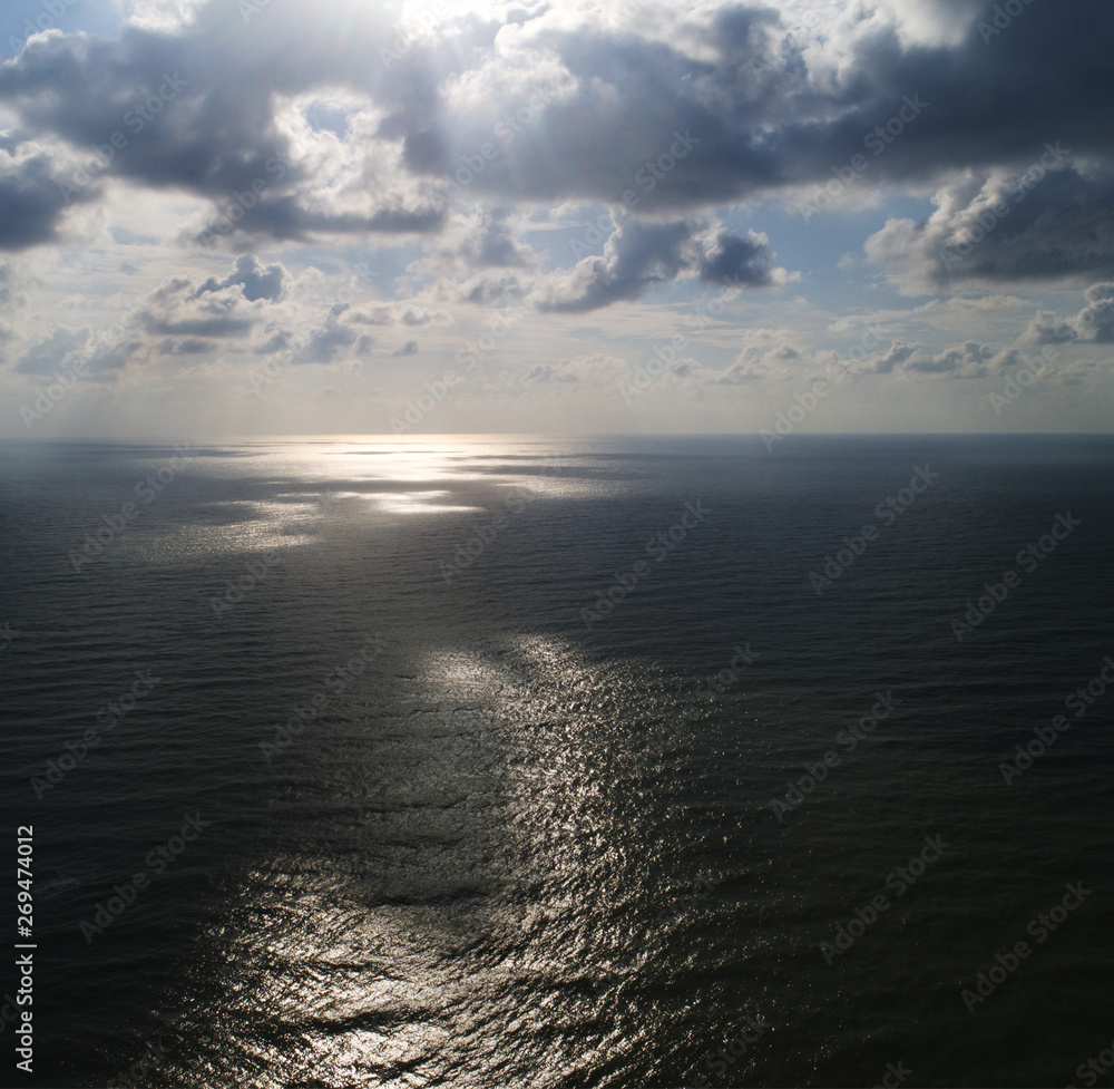 Aerial view. A calm sea with sun light beaming through the clouds. Aerial view. A calm sea with sun light beaming through the clouds.