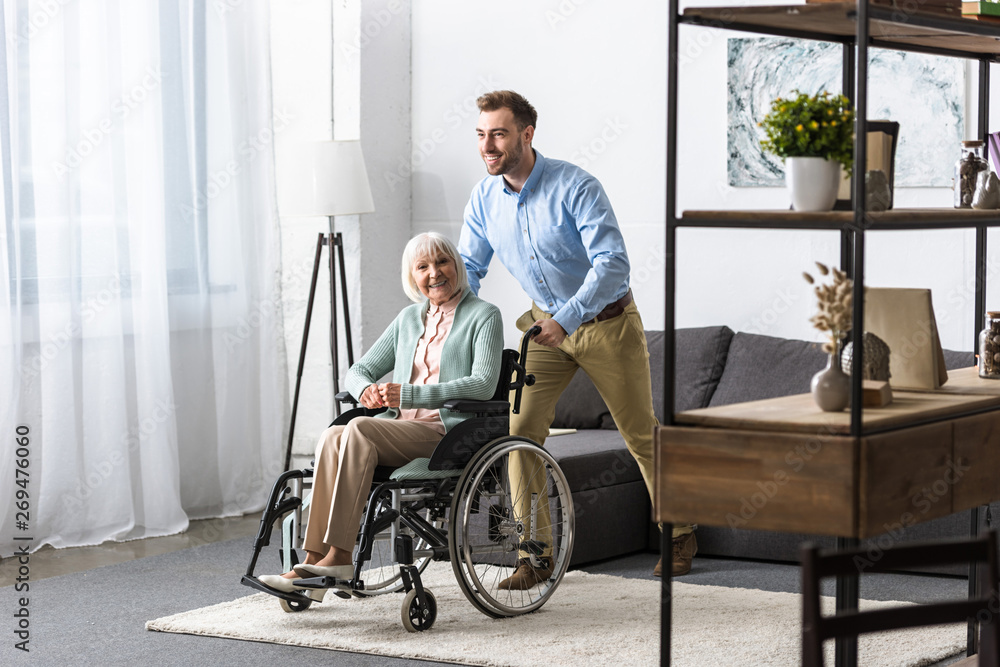 smiling man carrying disabled senior mother on wheelchair smiling man carrying disabled senior mother on wheelchair