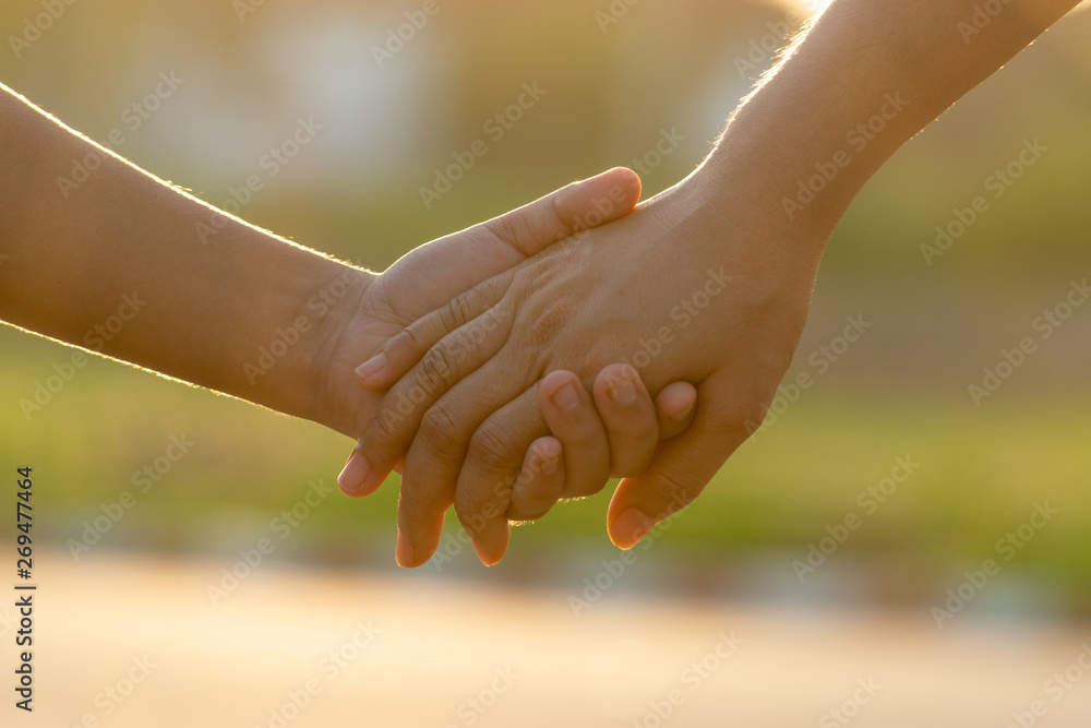 Close up of mother and a child hands at the sunset with copy space. Love concept or family concept. Close up of mother and a child hands at the sunset with copy space. Love concept or family concept.