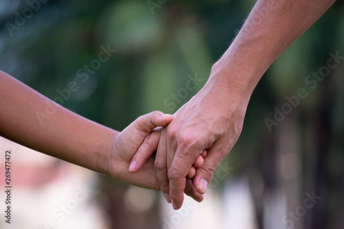 Close up of father and a child hands at the sunset with copy space. Love concept or family concept.