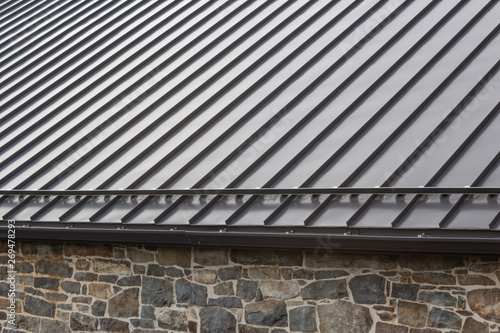 Canvas Print Standing seam modern metal roof over vintage stone wall, horizontal aspect