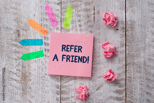 Handwriting text writing Refer A Friend. Conceptual photo direct someone to another or send him something like gift Plain note paper and line arrow stickers on the top of wooden table desk