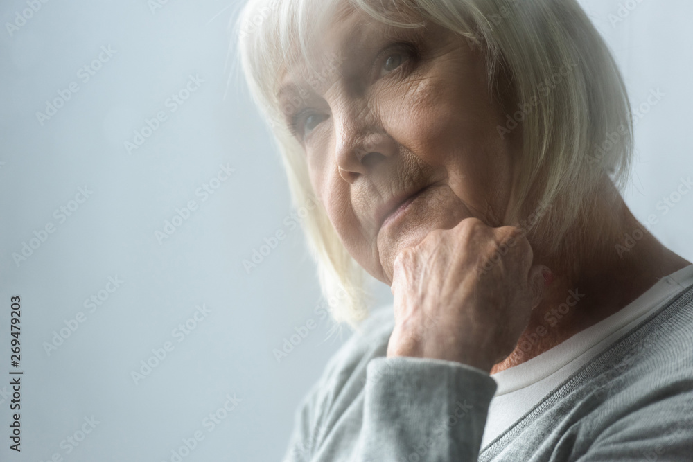 selective focus of pensive senior woman with grey hair propping face with hand selective focus of pensive senior woman with grey hair propping face with hand