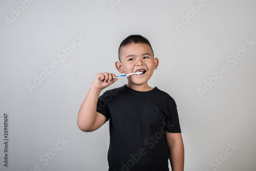 Little boy brushing his teeth in studio photo