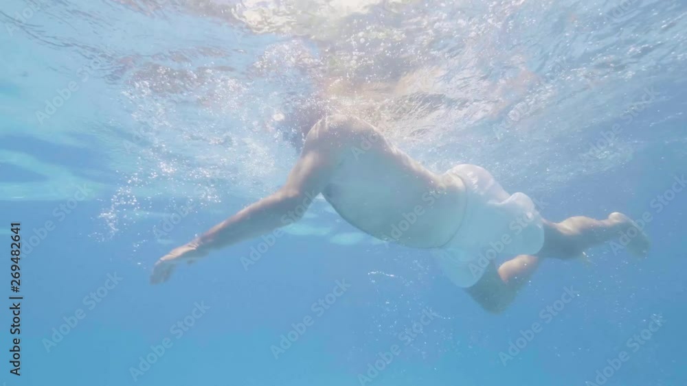 Male swimmer floating under blue water swimming pool. Underwater view adult man swimming in floating pool. Water sport. Senior activity. Male swimmer floating under blue water swimming pool. Underwater view adult man swimming in floating pool. Water sport. Senior activity.