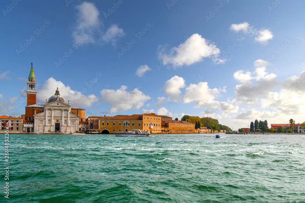 A small boat passes in front of San Giorgio Maggiore, the 16th century Church and tower on the island of San Giorgio Maggiore, in Venice, Italy.