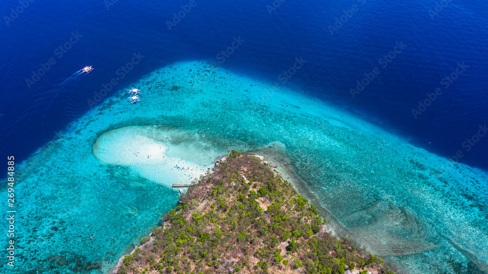 Aerial view of the Sumilon island, sandy beach with tourists swimming in beautiful clear sea water of the Sumilon island beach, Oslob, Cebu, Philippines.