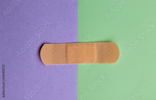 Adhesive bandage or Sticking plaster on a two colored paper background.